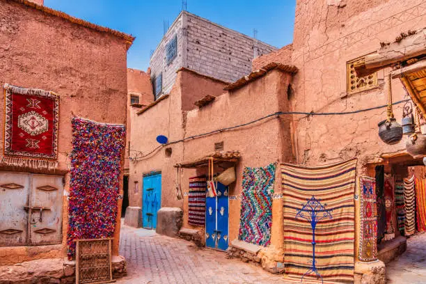 Colorful handmade Moroccan carpets and rugs displayed in a traditional souk, Majesty Morocco Tours.